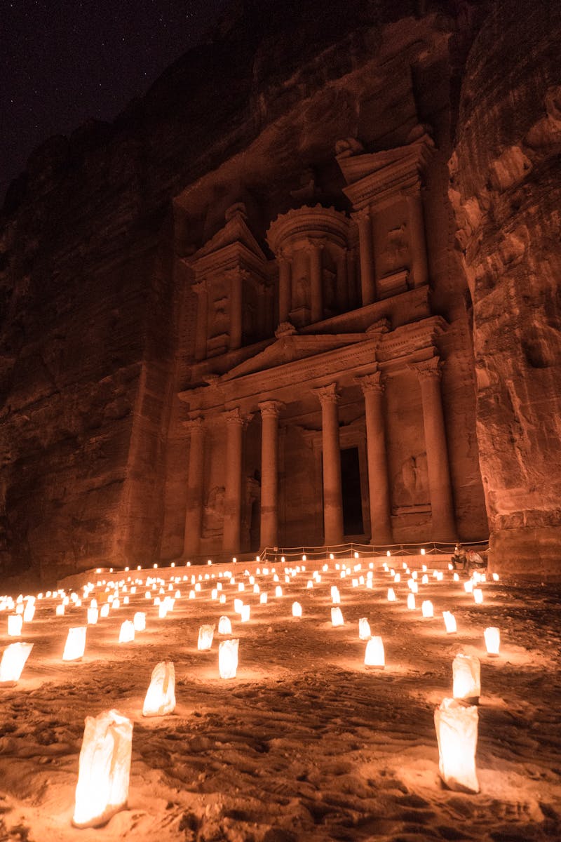 The Petra Treasury in Jordan, beautifully illuminated by candlelight during nighttime.